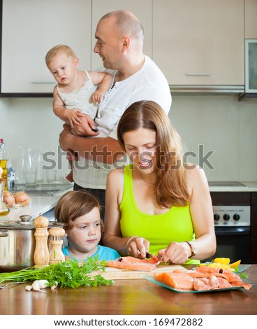 Cheerful family of four red cooking salmon on the home kitchen
