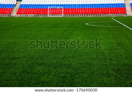 Green football field with stands colored in russian flag