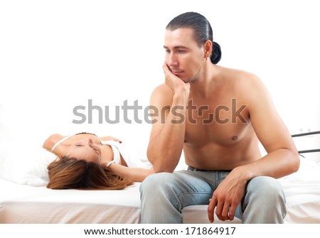 Sad man with problem in bed infront of his wife in bedroom