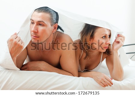Unhappy man and woman having  problem under sheet in bed