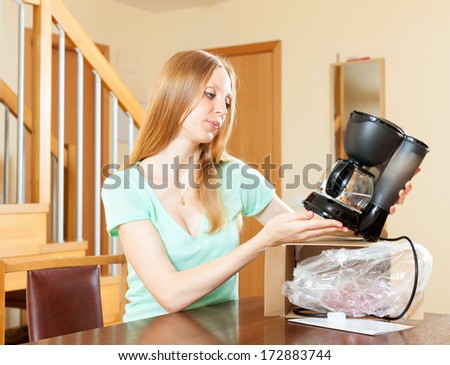 Beautiful young blond with new  coffee maker in home interior