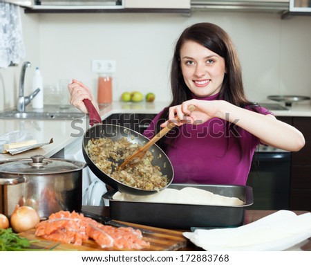 Smiling  woman cooking fish pie with salmon and vegetables