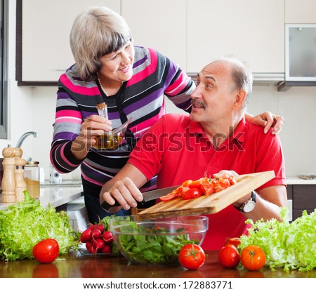 Elderly Couple Cooking With Tomatoes In Home Kitchen