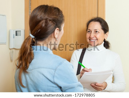 woman filling questionnaire for mature employee with paper at door