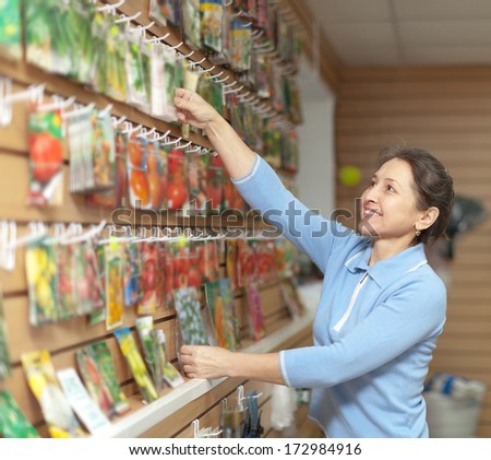 mature woman chooses packaged seeds at store