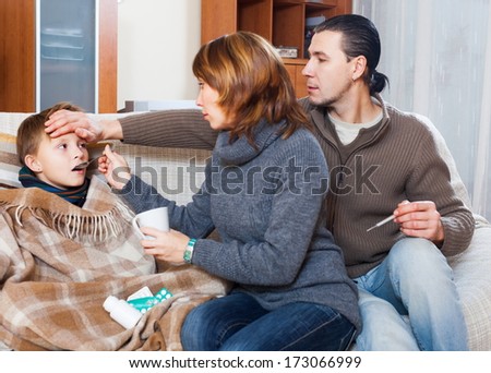 Caring parents and son with thermometer at home