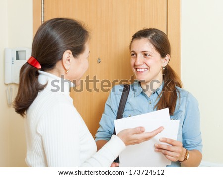 mature woman answer questions of smiling woman with papers at door