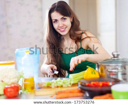 beautiful woman cuts green celery at her kitchen at home