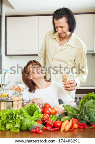 woman and handsome husband cooking with fresh vegetables at home kitchen