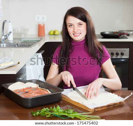 Smiling girl cooking fish pie with store-bought dough at home
