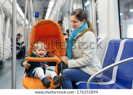 woman with crying child in stroller at subway train