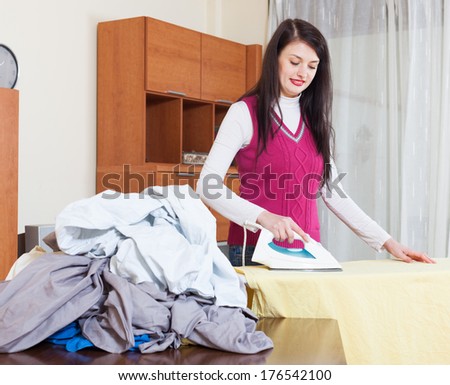 brunette woman ironing at ironing board in home