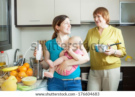 Happy family of three generations with blender cooking fruit puree in domestic kitchen at home