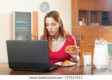 Young beautiful famale checking e-mail on laptop during breakfast time