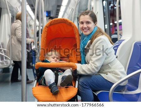 young mother with baby in stroller inside metro train