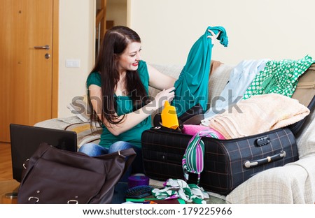 Happy brunette girl choosing dress for vacation at home
