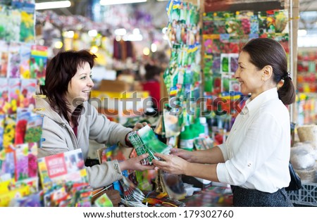 friendly woman selling seeds to mature buyer in store