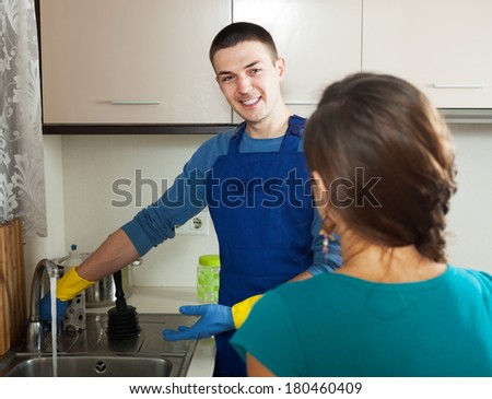 Smiling plumber repairing a running water  for  woman