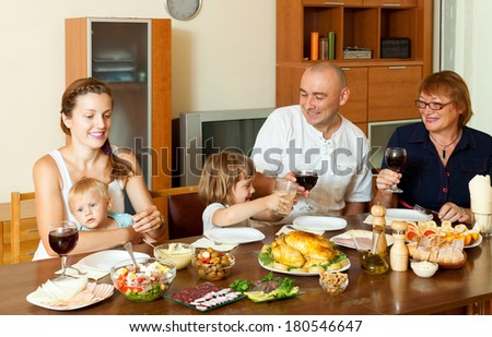 Portrait of happy family together over dining table eating chicken with wine at home interior