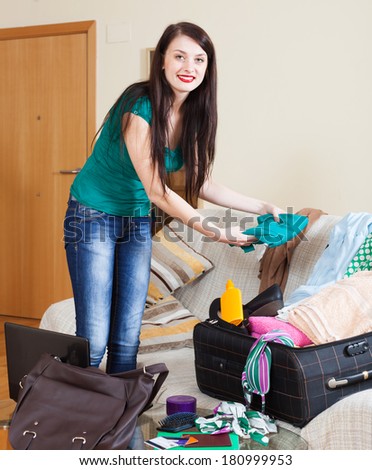 Smiling brunette woman packing suitcase for travel