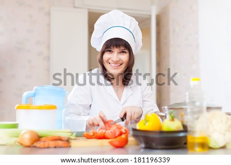 Positive female cook with celery on cutting board at kitchen