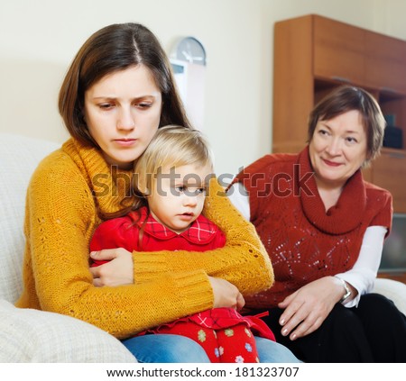 young sad mother with baby and mature grandmother  after quarrel at home
