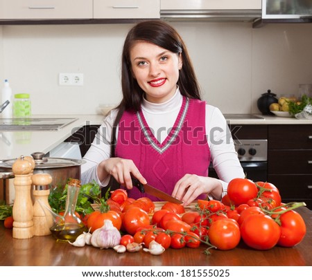 Happy woman cutting  tomatoes in home kitchen