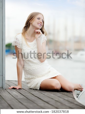 Portrait of long-haired pregnancy woman sitting near sea port