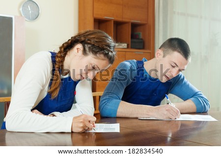 serious workers in uniform filling in questionnaire at table