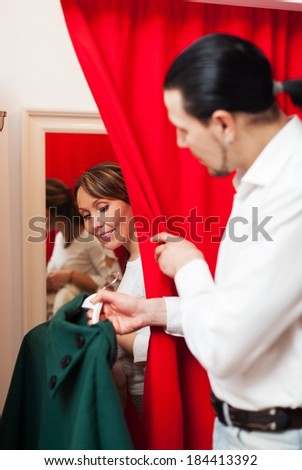 Man and woman choosing coat in fitting-room at market