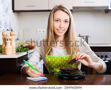 Smiling woman weighing chocolate on kitchen scales