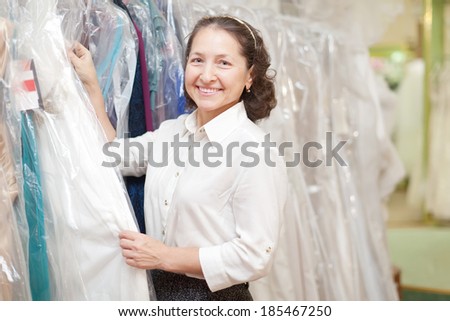 Smiling mature woman looking evening dress at boutique