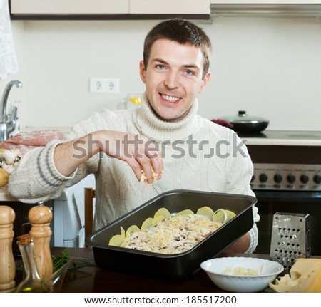 Guy cooking french-style veal. Adding grating cheese in roasting pan.