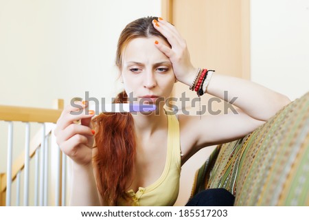 serious girl with pregnancy test at home interior
