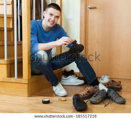 Smiling guy sitting on stairs and cleaning footwear