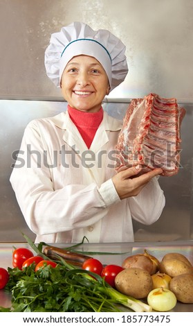 Cook woman with raw meat  in kitchen