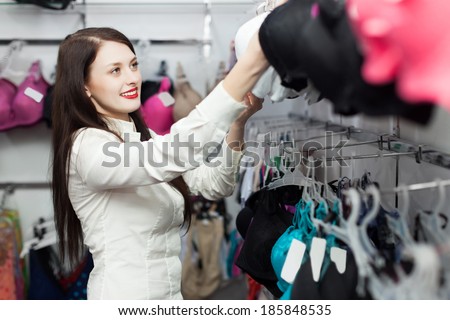Happy female buyer choosing bra at clothing shop