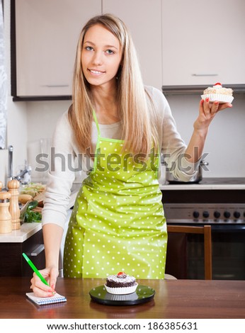 Woman in apron weighing cakes on kitchen scales