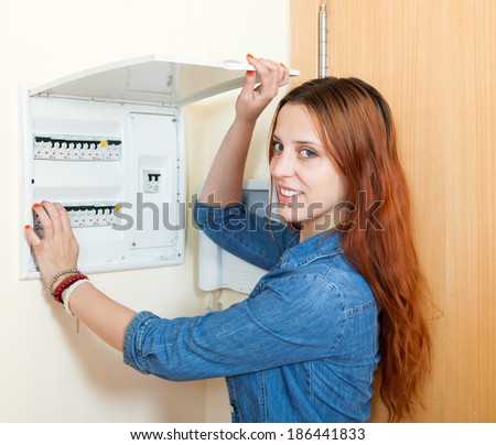 Smiling woman near power control panel at home