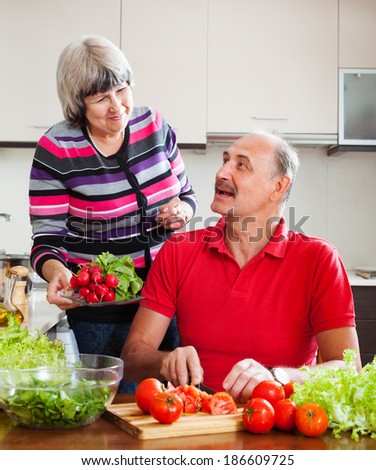 happy elderly couple cooking vegetables lunch in home kitchen