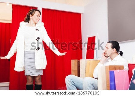 Man and woman choosing coat in fitting-room at shop