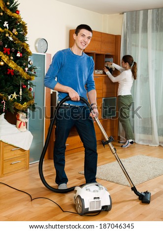 Adult couple cleaning with vacuum cleaner in living room