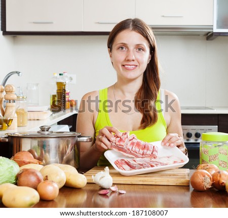 woman with lamb meat in home kitchen