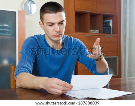 guy fills in financial documents at table in home interior