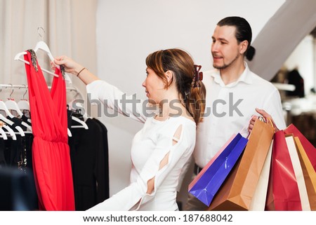 Couple with shopping bags choosing  dress at boutique