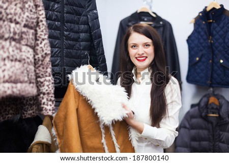 Smiling woman choosing jacket at clothing store