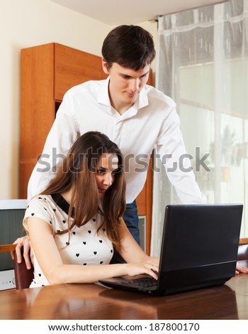 Happy couple  with laptop at table at home