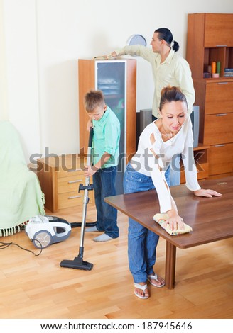 Teenager boy with parents dusting together in home