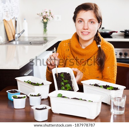 Girl working with green seedlings at table at home