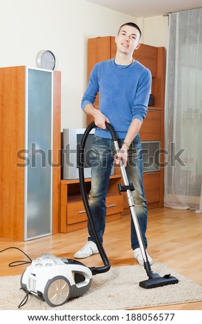 man with vacuum cleaner on parquet floor in living room